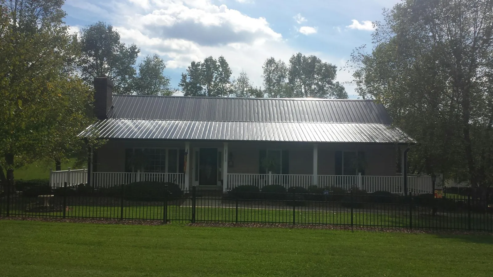 Gray metal roof on a brick ranch with a full width front porch — Gutter Guard Installation work by our crew in Erie